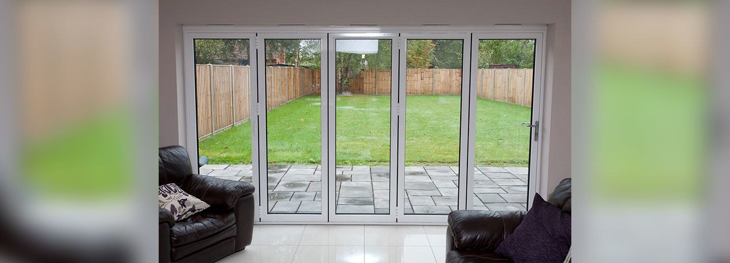 Contemporary white aluminium sliding doors opening onto a garden shown from inside