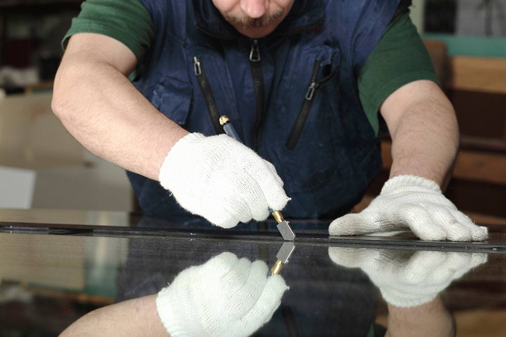 A professional glazier cuts glass to size for a special order